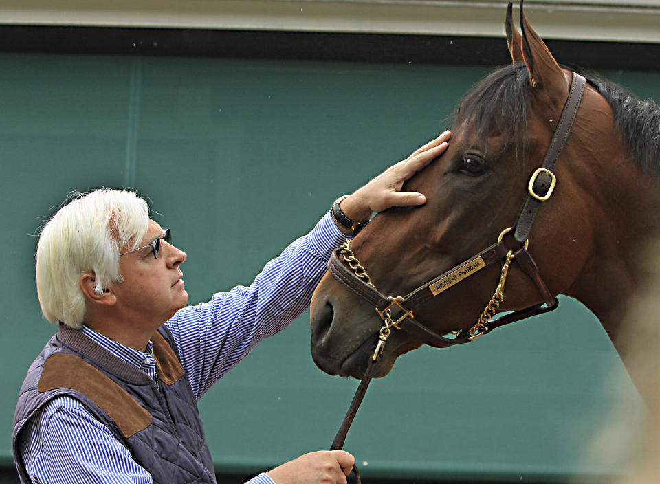 FILE - In this May 17, 2015, file photo, trainer Bob Baffert rubs the head of 2015 Kentucky Derby winner American Pharoah outside the stakes barn at Pimlico Race Course in Baltimore, May 17, 2015. Baffert will miss the race for the third consecutive year. He served a two-year suspension by Churchill Downs Inc. after his 2021 winner Medina Spirit was disqualified for a failed drug test. But the track’s corporate ownership meted out an additional year of punishment. (AP Photo/Garry Jones, File)