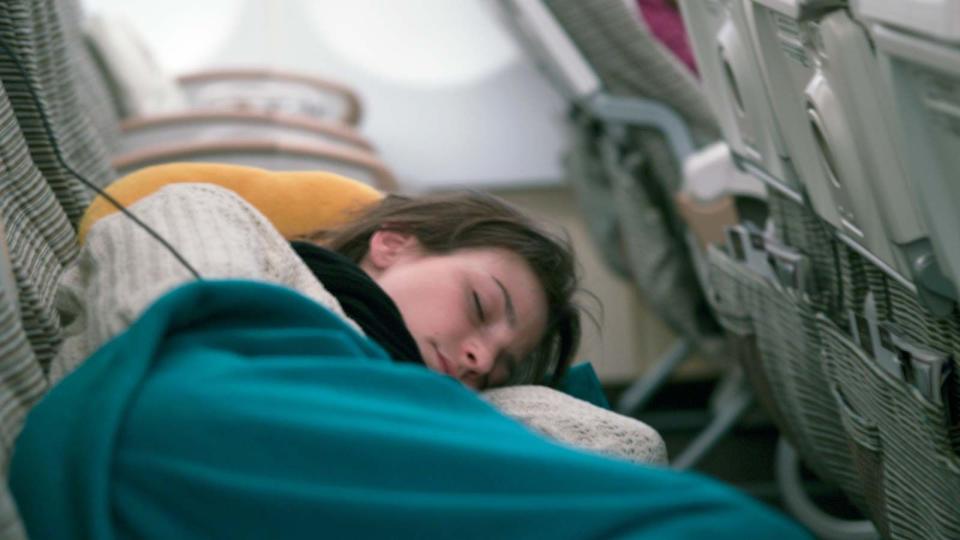 Young Woman Asleep In Airplane Cabin On Long Distance Flight Cold Temperature