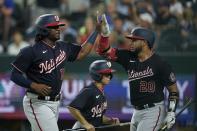 Washington Nationals' Josh Bell, left, and Keibert Ruiz (20) celebrate after Bell scored on a Luis Garcia double in the sixth inning of a baseball game against the Texas Rangers, Friday, June 24, 2022, in Arlington, Texas. (AP Photo/Tony Gutierrez)