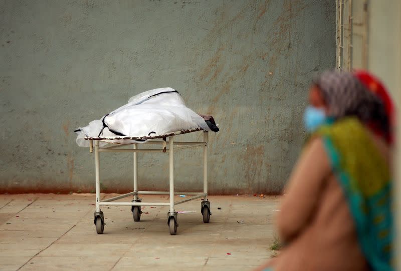 Relatives wait to receive the body of a man after he died from the COVID-19, outside a mortuary of a COVID-19 hospital in Ahmedabad