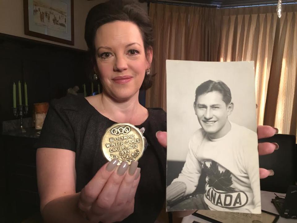 Jennifer Rattray holds her grandfather, Kenneth Moore's, Olympic gold medal and portrait. 
