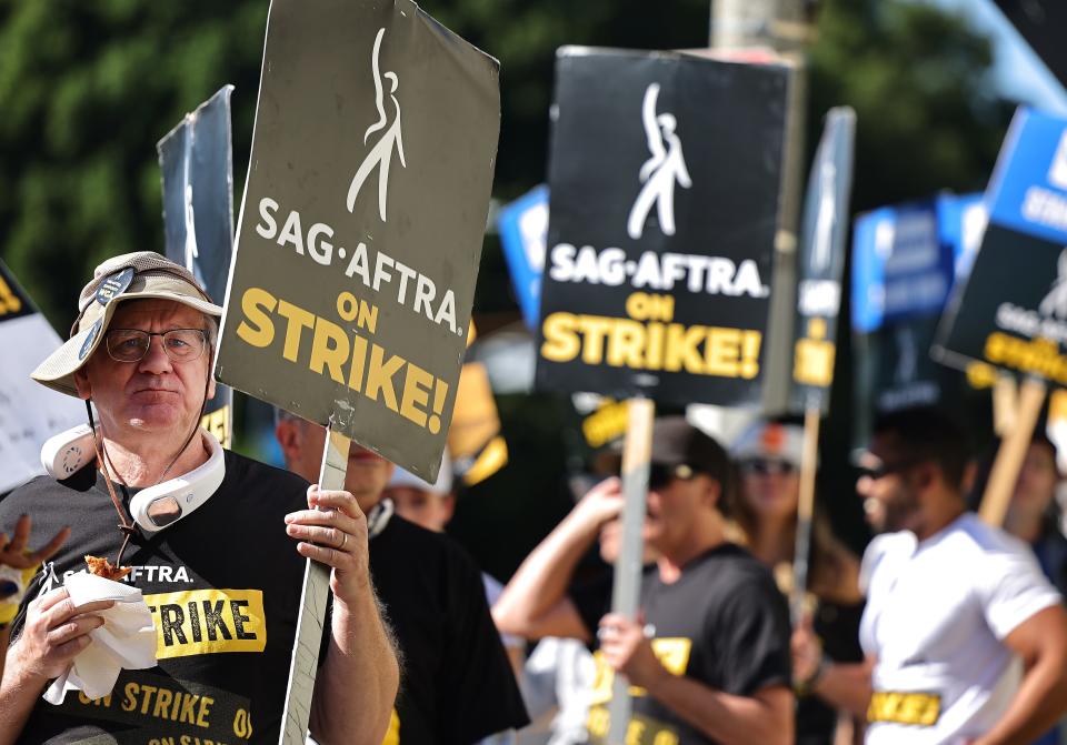 A picketer eats donated pizza for strikers as SAG-AFTRA members and supporters picket outside Paramount Studios on day 113 of their strike against the Hollywood studios on Nov. 3 in Los Angeles.