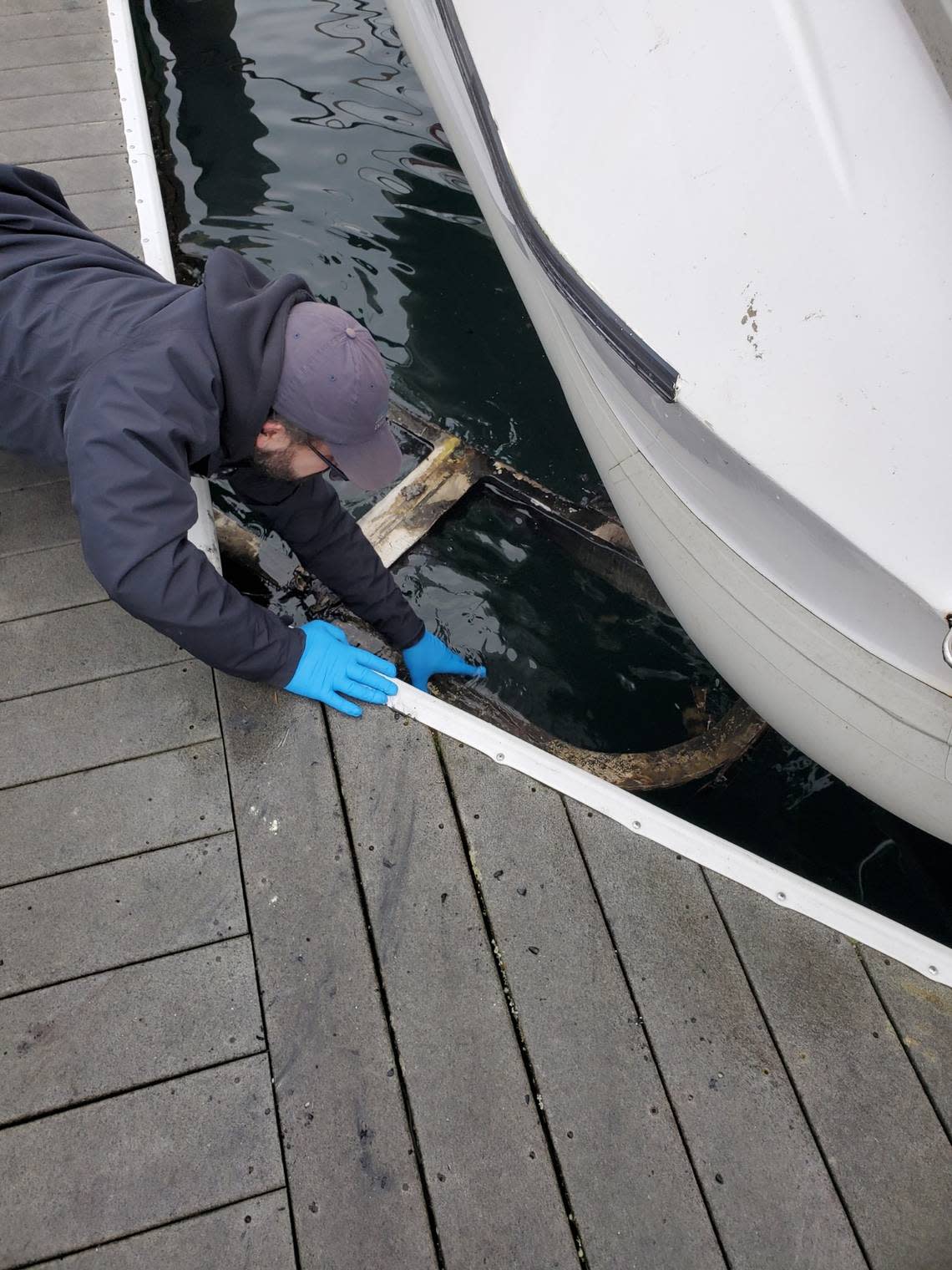 A dock hand pulls a burnt piece of the boat out of Thea Foss Waterway on Jan. 28, 2023.