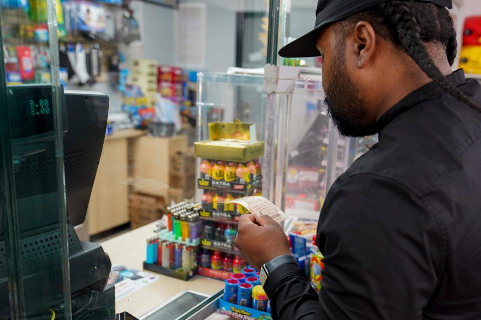 Malik Johnson, 36, of Detroit looks at the potential winning numbers of his purchased Mega Millions lottery ticket on Tuesday, Aug. 8, 2023. Some states allow lottery winners to collect anonymously,