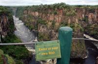 Victoria Falls, Zimbabwe: A sign warns tourists from proceeding from a lookout point over the Zambezi River below Victoria Falls, Zimbabwe. Called one of the world's seven natural wonders, Victoria Falls stretches 1708 meters, forming the world's largest waterfall.