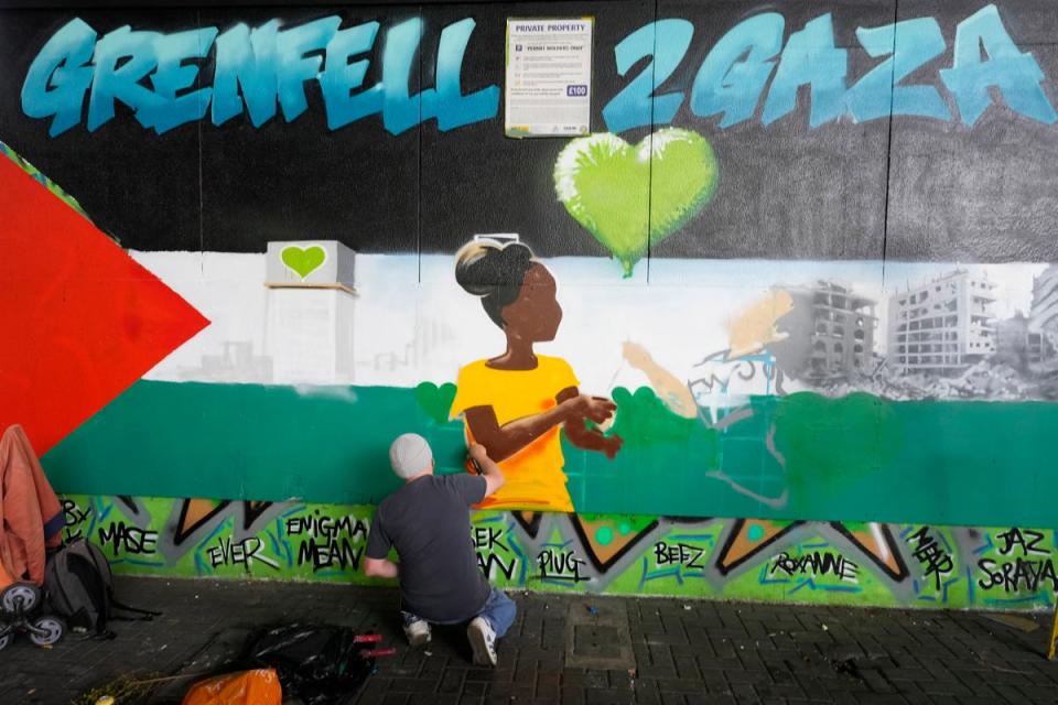 A street artist works in the Hope Gardens near Grenfell Tower (AP)