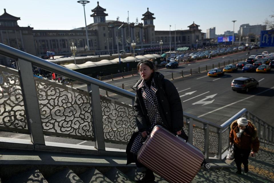 A woman carrying her bag walks up an overpass walkway outside the Beijing railway station in the Chinese capital on January 10, 2020, as people begin to head for their hometowns ahead of the Lunar New Year.