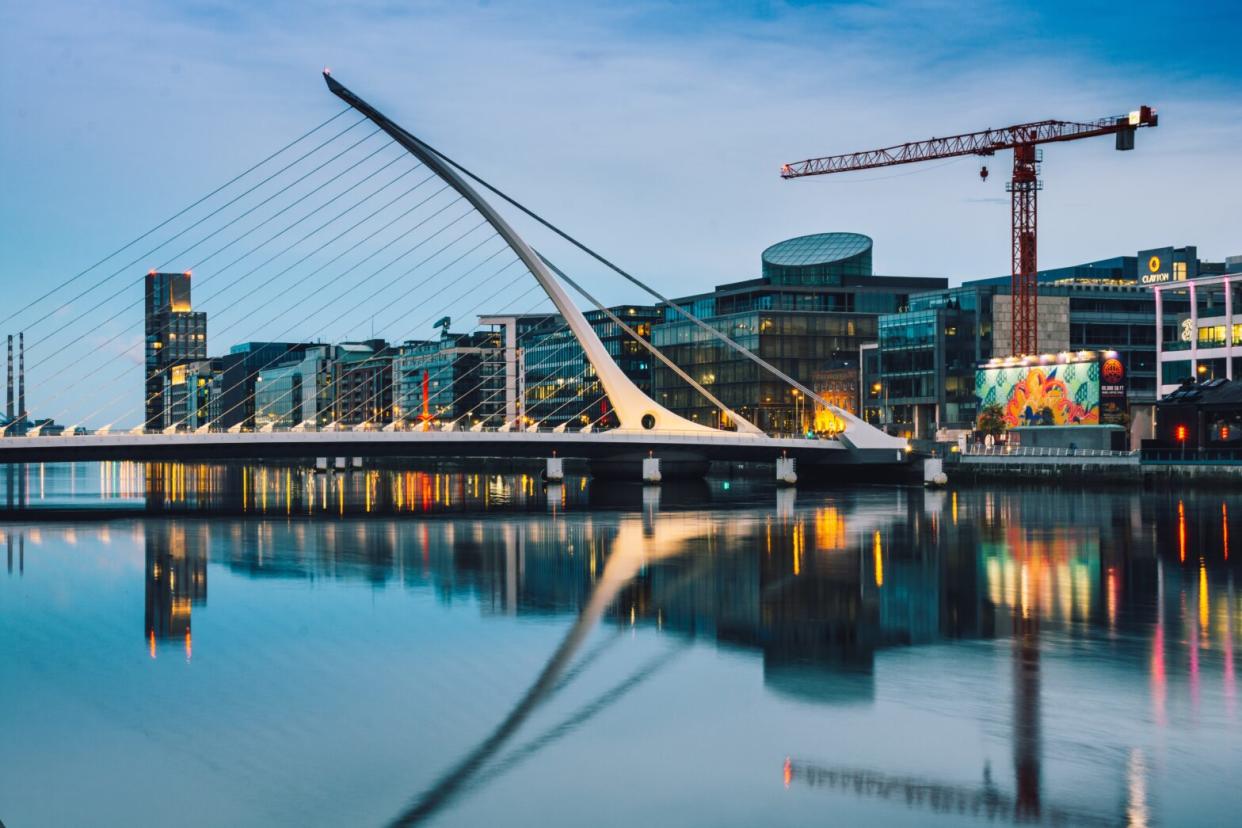 Pictured: The coast of Dublin, Ireland with hotels and a bridge. Dublin is a great city to tour on your own or with loved ones. Here are all the great places to stay in Dublin.