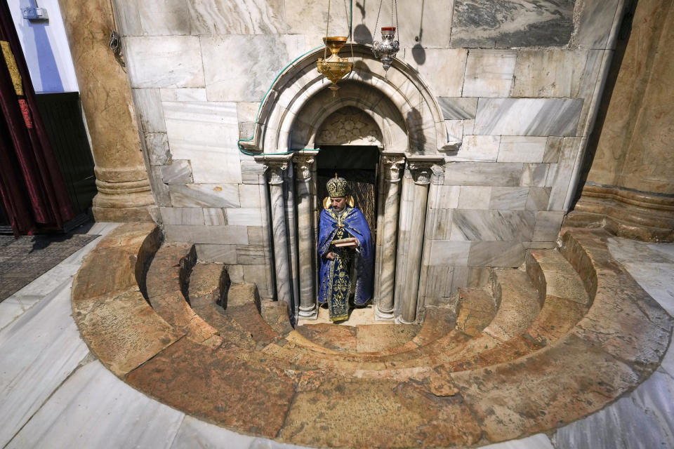 A was clergyman holds holy books inside the Church of the Nativity, traditionally believed to be the birthplace of Jesus Christ, in the West Bank town of Bethlehem, Saturday, Dec. 24, 2022. (AP Photo/Majdi Mohammed)