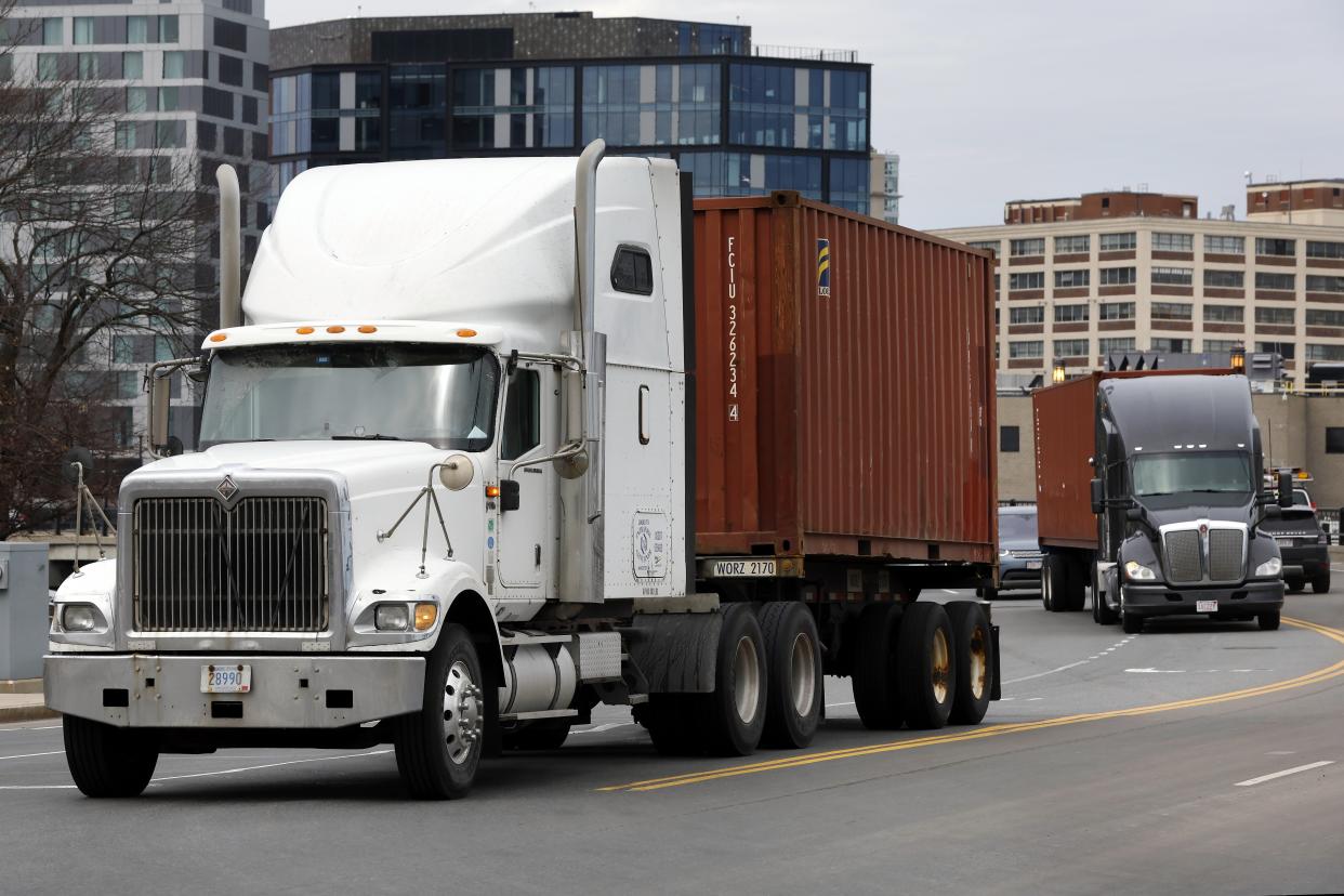 Trucks hauling shipping containers drive in Boston, Friday, March 17, 2023. (AP Photo/Michael Dwyer)