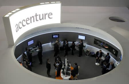 Visitors look at devices at Accenture stand at the Mobile World Congress in Barcelona, in this February 26, 2013, file photo. REUTERS/Albert Gea/Files