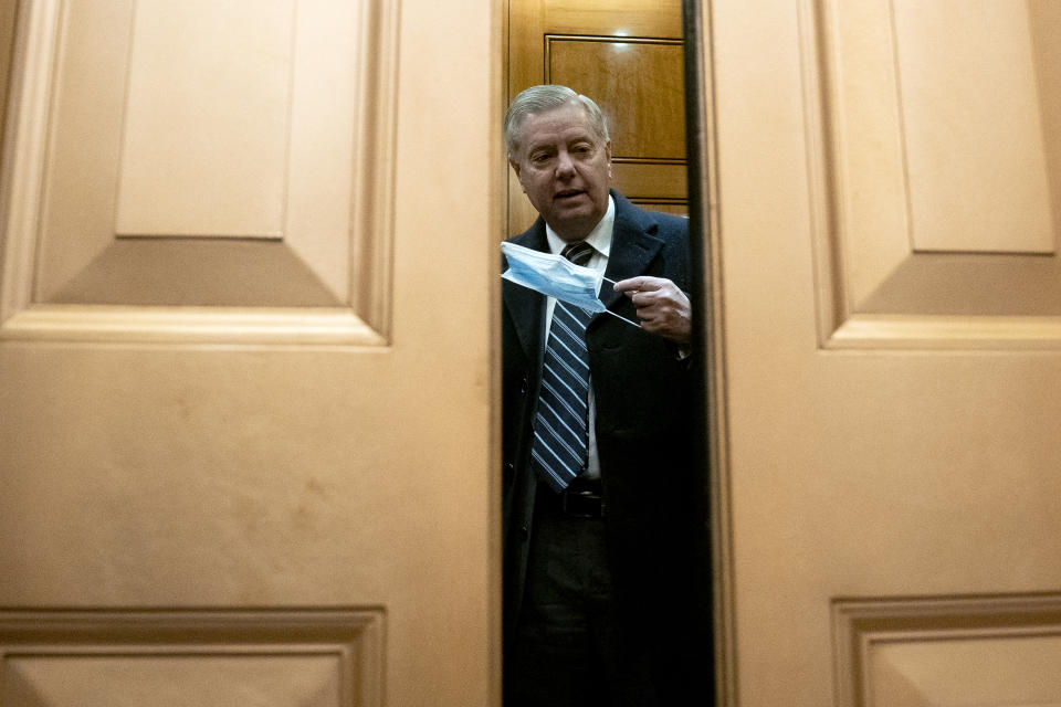 Sen. Lindsey Graham, R-S.C., puts on a face mask on the fifth day of the second impeachment trial of former President Donald Trump, Saturday, Feb. 13, 2021 at the Capitol in Washington. (Stefani Reynolds/Pool via AP)