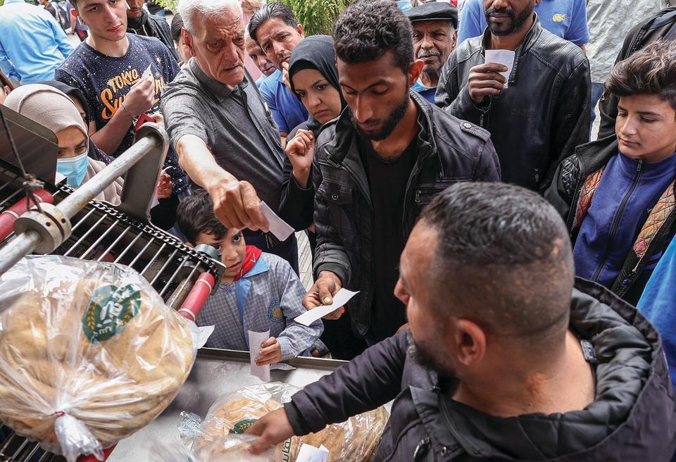 People queue to buy bread outside a bakery in Beirut, Lebanon April 12, 2022. - Credit: Mohamed Azakir/Reuters/Alamy