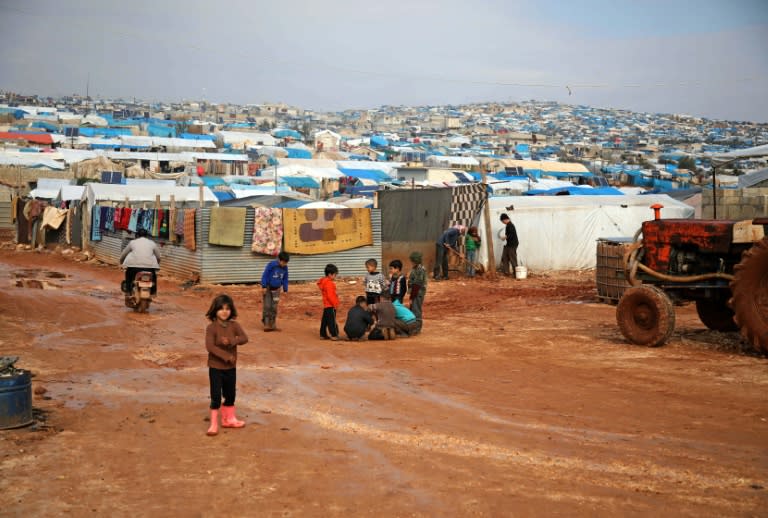 Children stand outside makeshift shelters following torrential rain that affected a camp for displaced people near the town of Atme close to the Turkish border in Syria's mostly rebel-held northern Idlib province on January 10, 2019