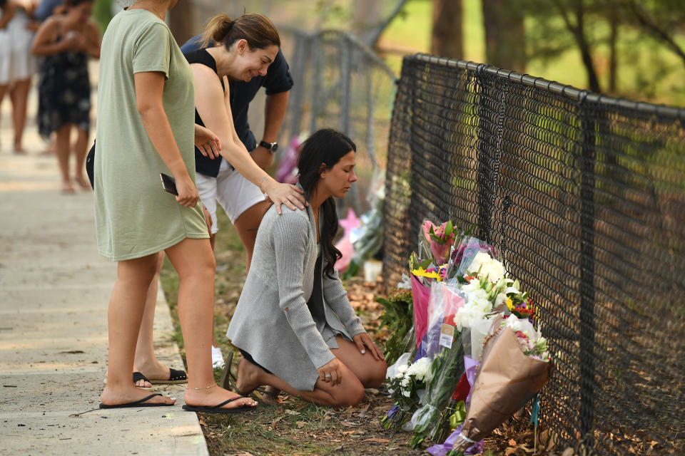 Leila Geagea, who lost three of her children in the crash, kneels to read tributes left. Source: AAP