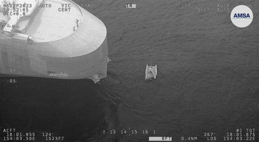 In this photo provided by the Australian Maritime Safety Authority, a partially submerged catamaran, right, is shown during a rescue of 3 sailors in the Coral Sea, Wednesday, Sept. 6, 2023. Three sailors from Russia and France were rescued on Wednesday after the inflatable catamaran they were trying to navigate from Vanuatu to Australia came under attack from sharks, authorities said. (Australian Maritime Safety Authority via AP)