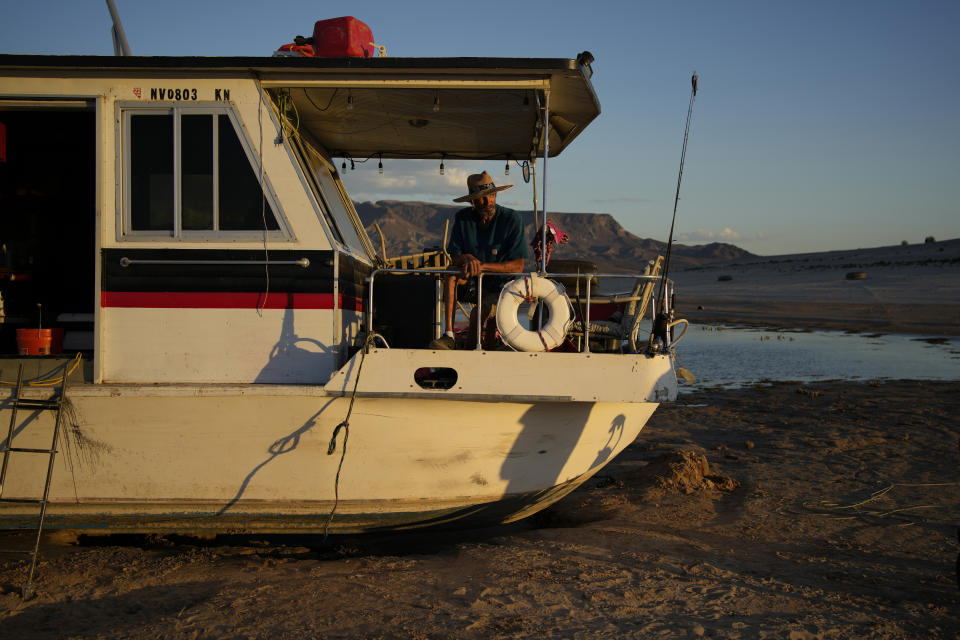 Craig Miller sentado en su casa flotante, que encalló en el lago Mead de Nevada, cerca de Boulder City, al bajar el nivel de las aguas. Foto del 23 de junio del 2022. (AP Photo/John Locher)