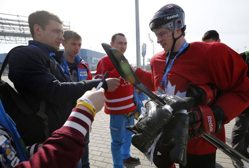 Canada's men's ice hockey team captain Sidney Crosby (R) signs autographs for fans after a team practice at the 2014 Sochi Winter Olympics, February 22, 2014. REUTERS/Jim Young (RUSSIA - Tags: SPORT OLYMPICS ICE HOCKEY)