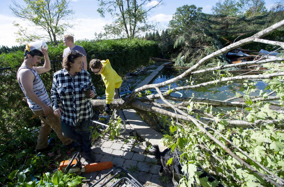 <p>Christine Earle, her sons Iain, left, Aidan, right, and friend Brandon Bates look at branches and building material swept into her pool by a tornado at her farm in Dunrobin, Ont., west of Ottawa, on Saturday, Sept. 22, 2018. The storm tore roofs off of homes, overturned cars and felled power lines in the Ottawa community of Dunrobin and in Gatineau, Que. (Photo from Justin Tang/The Canadian Press) </p>