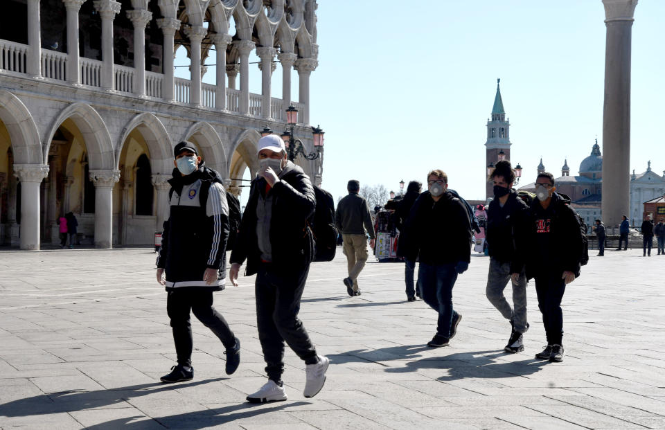 Tourists wearing a protective face mask walk on San Marco square in Venice on March 8, 2020. - A quarter of the Italian population was locked down on March 8, 2020 as the government takes drastic steps to stop the spread of the deadly new coronavirus that is sweeping the globe, with Latin America recording its first fatality. (Photo by ANDREA PATTARO / AFP) (Photo by ANDREA PATTARO/AFP via Getty Images)