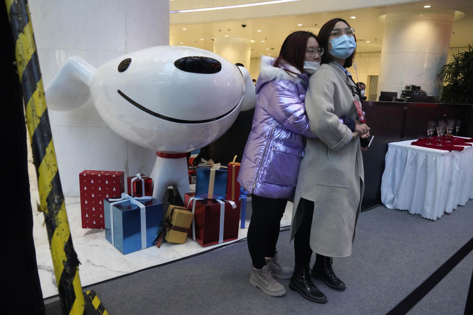 Attendees stand near the mascot for JD.com during a ceremony to mark the listing of JD Health, an arm of JD.com, on the Hong Kong Stock Exchange at the JD Headquarters in Beijing Tuesday, Dec. 8, 2020. Shares in China's biggest online health care platform rose 40% in their Hong Kong stock market debut Tuesday, reflecting investor enthusiasm for the fledgling industry as the country emerges from the coronavirus pandemic. (AP Photo/Ng Han Guan)