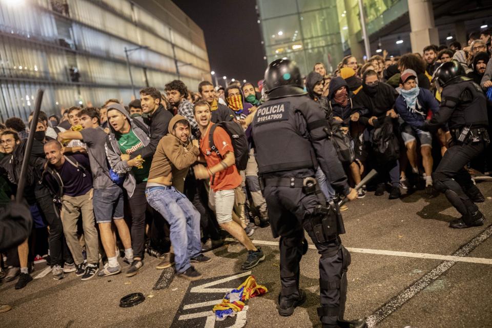 Police clash with protesters during a demonstration at El Prat airport, outskirts of Barcelona, Spain, Monday, Oct. 14, 2019. Spain's Supreme Court on Monday sentenced 12 prominent former Catalan politicians and activists to lengthly prison terms for their roles in a 2017 bid to gain Catalonia's independence, sparking protests across the wealthy Spanish region. (AP Photo/Bernat Armangue)