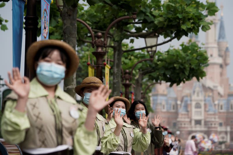 Staff members wearing protective face masks greet at Shanghai Disney Resort as the Shanghai Disneyland theme park reopens following a shutdown due to the coronavirus disease (COVID-19) outbreak, in Shanghai