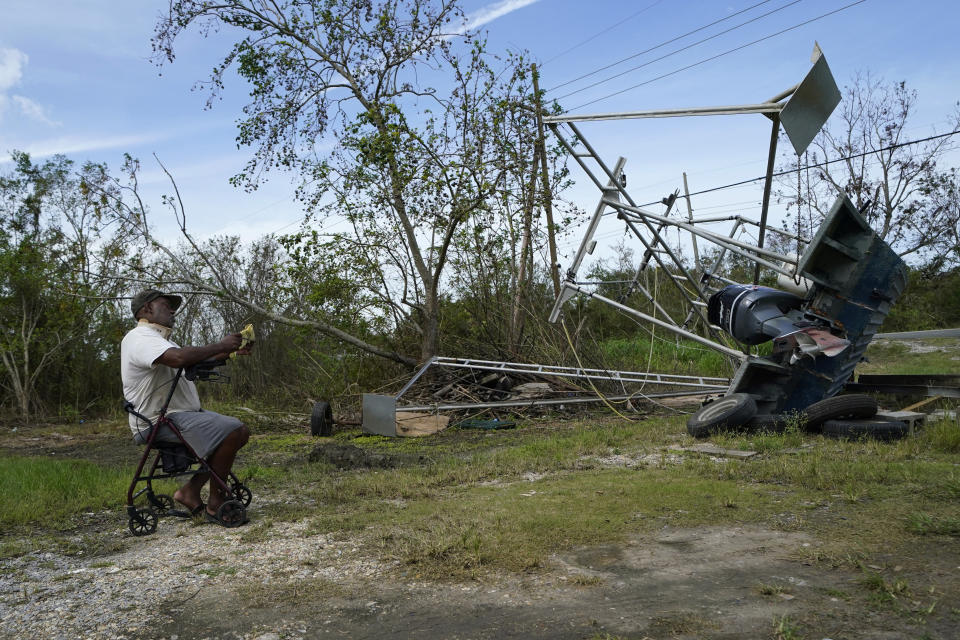 Dale Williams, who cannot speak due to a tracheotomy from cancer, writes on a pad next to his shrimp trawler that overturned and cracked during Hurricane Ida, in Plaquemines Parish, La., Monday, Sept. 13, 2021. Ida's Category 4 winds flipped Williams' trawler on its side, bending the frame and tearing nets, but it should be ready to go after about $1,500 in repairs, he said in an interview conducted by written notes. (AP Photo/Gerald Herbert)