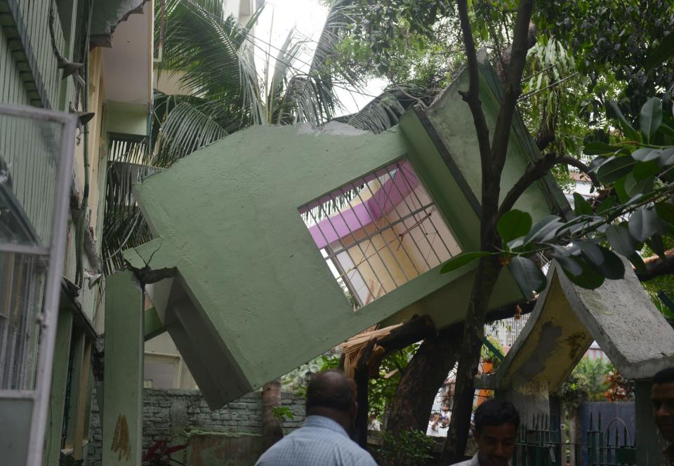 Indian bystanders look at a collapsed house in Siliguri on April 25, 2015. (DIPTENDU DUTTA/AFP/Getty Images)