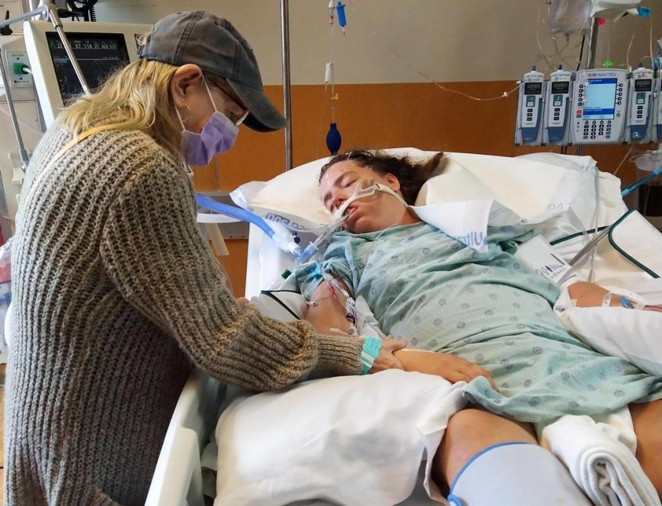 Peggie Griggs holds her granddaughter’s hand at JPS Hospital, where Kelly Masten was transferred after 10 days at the Tarrant County Jail. Masten’s family said she has a seizure disorder that went untreated during her incarceration.