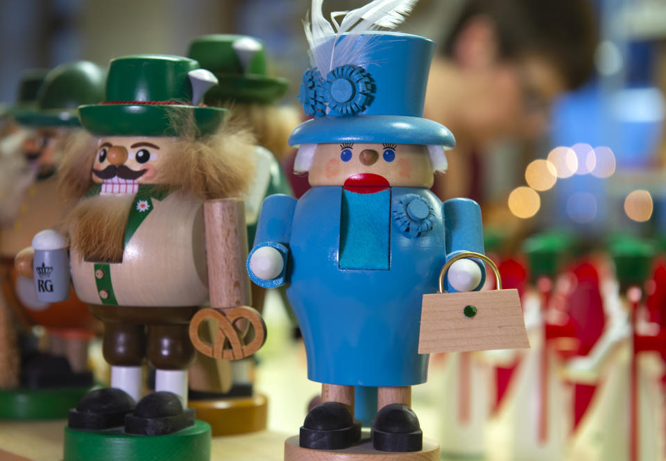 A woman works behind a nutcracker displaying the British Queen Elizabeth II, right, in the Richard Glaesser company, manufacturer of traditionally hand-made wooden Christmas decoration, in the toy village Seiffen, eastern Germany, Dec. 15, 2019. (AP Photo/Jens Meyer)