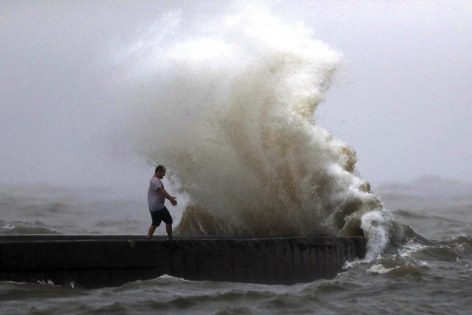 FILE - A wave crashes as a man stands on a jetty near Orleans Harbor in Lake Pontchartrain in New Orleans, June 7, 2020, as Tropical Storm Cristobal approaches the Louisiana Coast. A new study says that back-to-back hurricanes that hit the same general place in the United States seem to be happening more often. (AP Photo/Gerald Herbert, File)