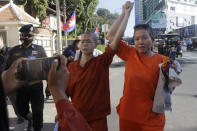 Theary Seng, center, a Cambodian-American lawyer, dressed in a prison-style orange outfit, raises hands with her supporter as she walks in front of Phnom Penh Municipal Court in Phnom Penh, Cambodia, Tuesday, Jan. 4, 2022. Cambodian security forces on Tuesday briefly detained Theary, a prominent rights activist, as she walked barefoot near the prime minister’s residence in Phnom Penh, wearing the orange outfit and Khmer Rouge-era ankle shackles. She was released, shortly afterwards, and arrived at the Phnom Penh court for the resumption of her trial on treason charges. (AP Photo/Heng Sinith)