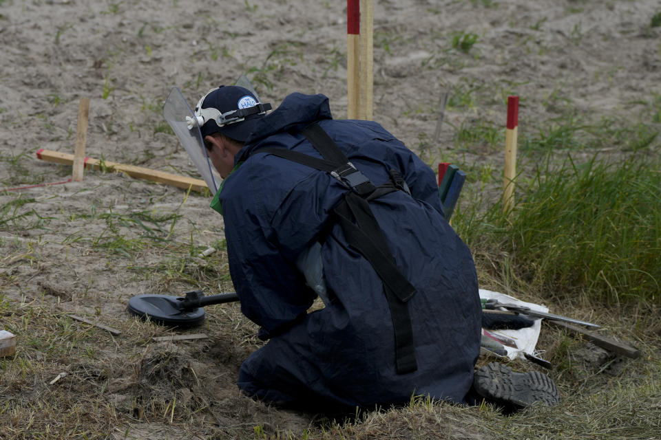 A mine detection worker with the HALO Trust de-mining NGO searches for anti-tank and anti personnel land mines in Lypivka, on the outskirts of Kyiv, Ukraine, Tuesday, June 14, 2022. Russia’s invasion of Ukraine is spreading a deadly litter of mines, bombs and other explosive devices that will endanger civilian lives and limbs long after the fighting stops. (AP Photo/Natacha Pisarenko)