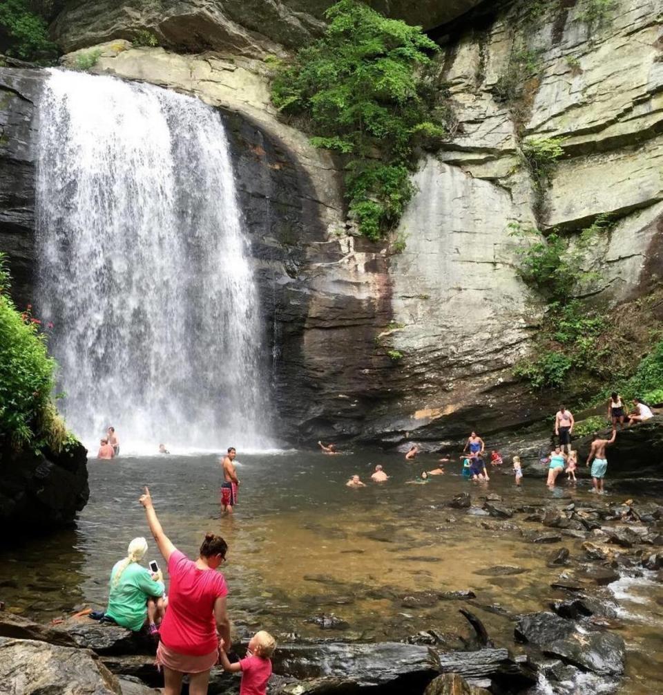 Visitors splash, swim and take photos on July 25, 2016, at the Looking Glass Falls in the Pisgah National Forest, west of Brevard, NC. The 60-foot falls is a popular stop for travelers, offering ample parking and easy steps that lead to two observation points and access to the swimming pool at its base.