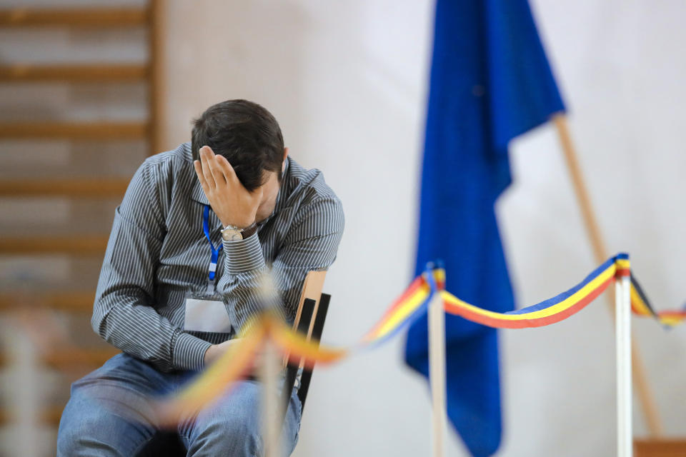 An election official touches his forehead at a voting station in Bucharest, Romania, Sunday, Nov. 24, 2019. Romanians are voting in a presidential runoff election in which incumbent Klaus Iohannis is vying for a second term, facing Social Democratic Party leader Viorica Dancila, a former prime minister, in Sunday's vote. (AP Photo/Vadim Ghirda)