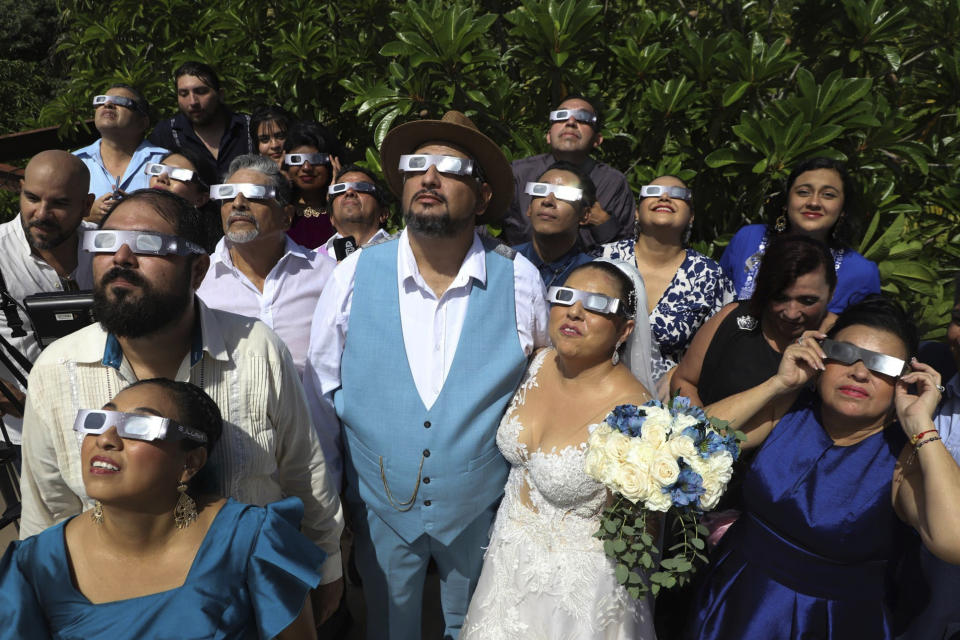 FILE - Groom Isaac Medina, center, and bride Jazmin Gonzalez, watch an annular solar eclipse, better known as a ring of fire, before the start of their wedding ceremony, in Merida, Mexico, Oct. 14, 2023. (AP Photo/Martin Zetina, File)