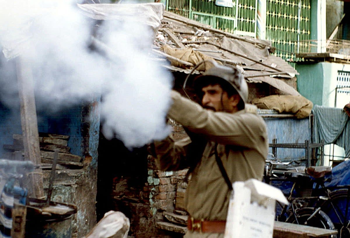 An Indian policeman shoot tear gas onto rioters in Ahmedabad on 5 April 2002 (AFP via Getty Images)