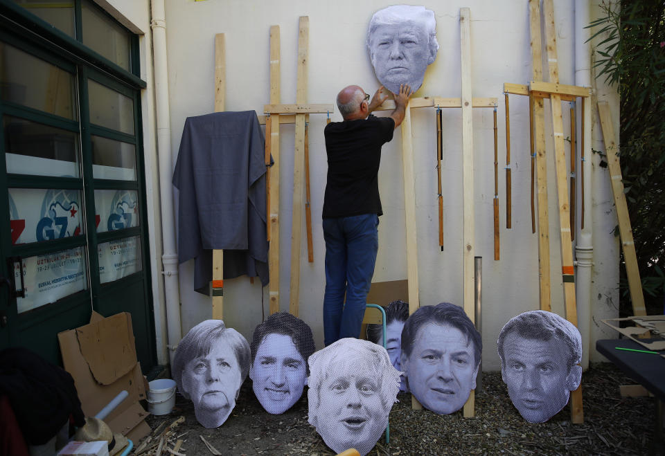 A man fixes an image of President Donald Trump to a wooden pole as he prepares for an anti-G-7 demonstration at a camp near Hendaye, France Friday, Aug. 23, 2019. U.S. President Donald Trump will join host French President Emmanuel Macron and the leaders of Britain, Germany, Japan, Canada and Italy for the annual G-7 summit in the nearby elegant resort town of Biarritz. Other leaders faces on show are from left: German Chancellor Angela Merkel, Canadian Prime Minister Justin Trudeau, Britain's Prime Minister Boris Johnson, Japanese Prime Minister Shinzo Abe, Italian Premier Giuseppe Conte and French President Emmanuel Macron. (AP Photo/Francois Mori)