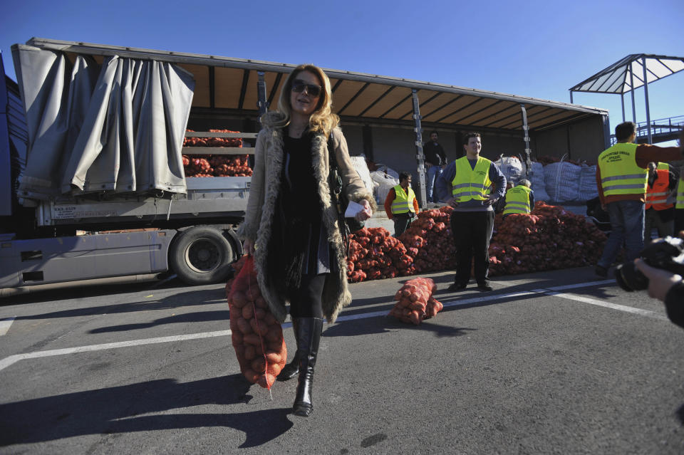 A customer carrying a 10 kg sack of potatoes sold at cost price in the northern Greek town of Katerini, Greece on Saturday, Feb. 25 2012. Farmers in northern Greece have joined forces with local residents to provide cheap produce to people whose family budgets have been slashed by the financial crisis, and also to help producers who say they are being squeezed by middlemen. Hundreds of families turned up Saturday in this northern Greek town to buy potatoes at massively reduced prices, sold directly by producers at cost price. (AP Photo/Nicolas Giakoumidis)