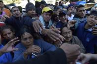 <p>Venezuelan citizens who remain in an improvised camp by the bus terminal in the north of Quito, Ecuador, reach for donations on Aug. 9, 2018. (Photo: Rodrigo Buendia/AFP/Getty Images) </p>