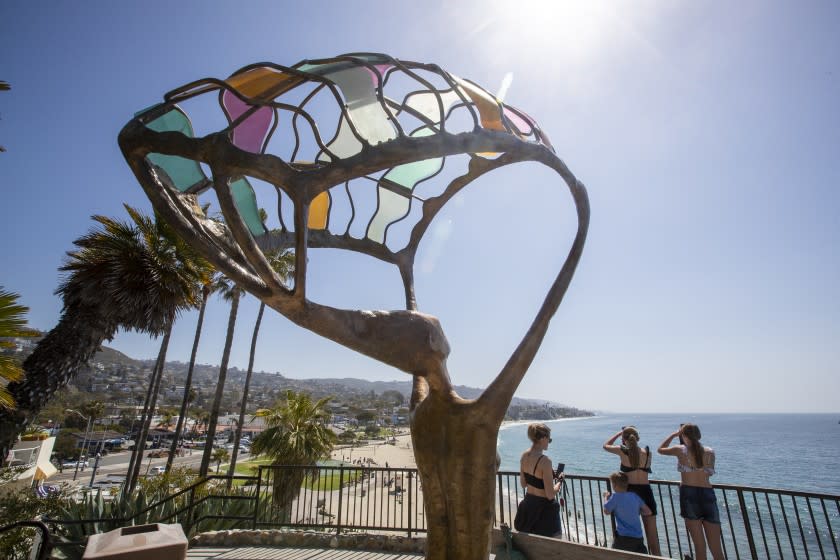 LAGUNA BEACH, CA - March 30: Amid pleasant weather, visitors take photos and take in the scenic view of Main Beach in Laguna Beach Tuesday, March 30, 2021. Orange County is moving into the state's less-restrictive orange tier as COVID-19 cases continue a downward trend and a windfall of vaccines rolls in. ``The numbers look good, and -- barring anything unforeseen -- we expect (Tuesday) to be on the orange tier list,'' Orange County CEO Frank Kim said. The state updates its weekly averages on Tuesdays based on statistics reported as of Sunday -- so if the numbers county officials have are accurate, the county could qualify for the orange tier on Tuesday and officially move into it on Wednesday. (Allen J. Schaben / Los Angeles Times)