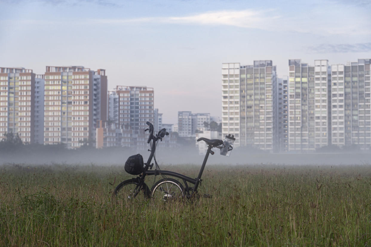A bicycle in front of a row of apartment blocks, with vapour in the air illustrating high humidity in Singapore.
