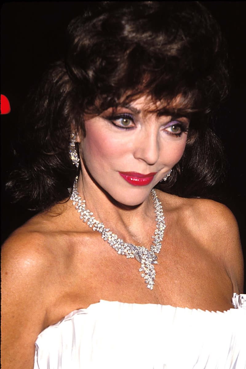 Joan Collins pictured with shiny berry-coloured lipstick