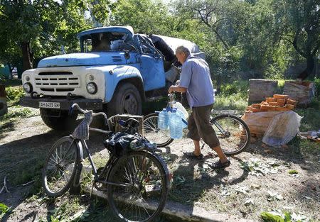 A man walks by a damaged truck as he transports water in the Ukrainian eastern city of Slaviansk July 1, 2014. REUTERS/Shamil Zhumatov