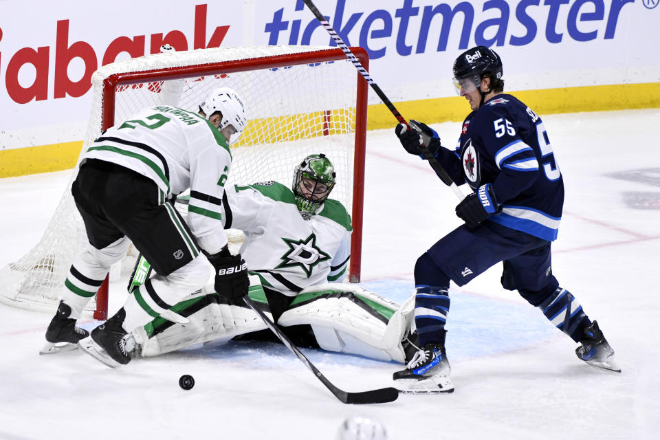 Winnipeg Jets' Mark Scheifele (55) looks for the rebound after a save by Dallas Stars' goaltender Scott Wedgewood (41) as Jani Hakanpaa (2) defends during the third period of an NHL hockey match in Winnipeg, Manitoba, on Saturday, Nov. 11, 2023. (Fred Greenslade/The Canadian Press via AP)