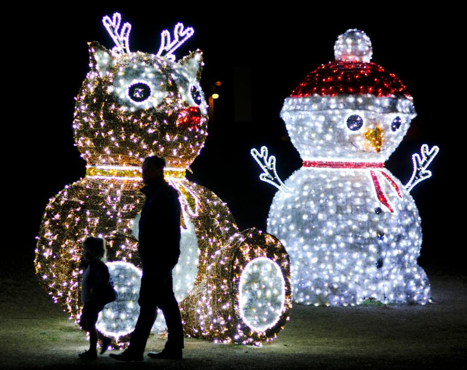 People walk through the Luminance holiday light display in Mitch Park in Edmond Thursday, December 2, 2021.