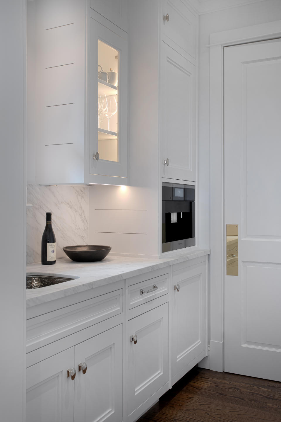 A white kitchen with marble countertops and inset kitchen cabinetry