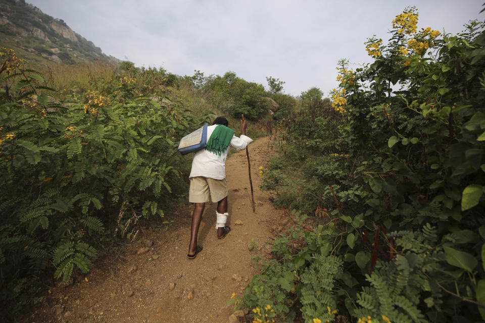 Kalmane Kamegowda, a 72-year-old shepherd, walks towards one of the 16 ponds he created at a hillock near Dasanadoddi village, 120 kilometers (75 miles) west of Bengaluru, India, Wednesday, Nov. 25, 2020. Kamegowda, who never attended school, says he's spent at least $14,000 from his and his son’s earnings, mainly through selling sheep he tended over the years, to dig a chain of 16 ponds on a picturesque hill near his village. (AP Photo/Aijaz Rahi)