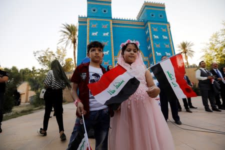 Children hold Iraqi flags during celebration after UNESCO designated ancient city of Babylon as World Heritage Site, in front of a replica of Ishtar gatee near Hilla